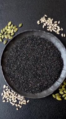 Bir kasede siyah susam tohumu, yağ ve sağlıklı yemek için bir malzeme. Tasarımınız için yiyecek arkaplanı olarak siyah susam