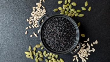 Bir kasede siyah susam tohumu, yağ ve sağlıklı yemek için bir malzeme. Tasarımınız için yiyecek arkaplanı olarak siyah susam