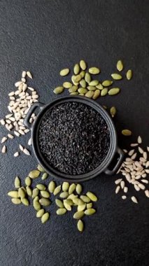 Bir kasede siyah susam tohumu, yağ ve sağlıklı yemek için bir malzeme. Tasarımınız için yiyecek arkaplanı olarak siyah susam