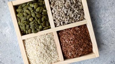 Bir kutu keten, balkabağı, ayçiçeği ve susam tohumu, sağlıklı beslenmek için malzemeler. Keten, susam, balkabağı ve ay çekirdeği tasarımınız için bir besin kaynağı.