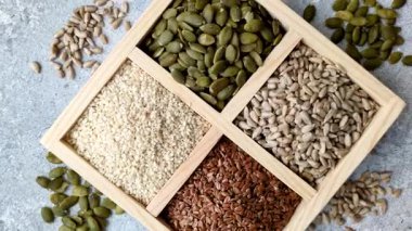 Bir kutu keten, balkabağı, ayçiçeği ve susam tohumu, sağlıklı beslenmek için malzemeler. Keten, susam, balkabağı ve ay çekirdeği tasarımınız için bir besin kaynağı.