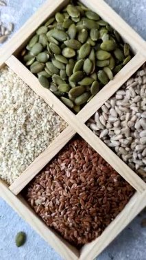 Bir kutu keten, balkabağı, ayçiçeği ve susam tohumu, sağlıklı beslenmek için malzemeler. Keten, susam, balkabağı ve ay çekirdeği tasarımınız için bir besin kaynağı.