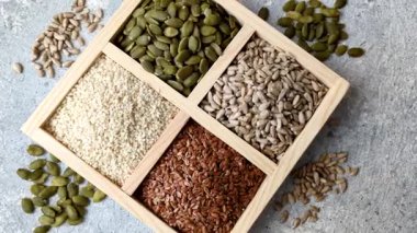 Bir kutu keten, balkabağı, ayçiçeği ve susam tohumu, sağlıklı beslenmek için malzemeler. Keten, susam, balkabağı ve ay çekirdeği tasarımınız için bir besin kaynağı.