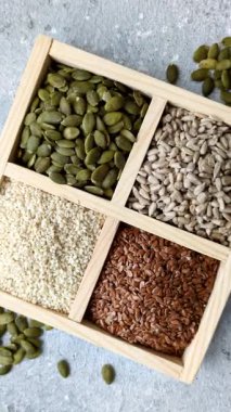 Bir kutu keten, balkabağı, ayçiçeği ve susam tohumu, sağlıklı beslenmek için malzemeler. Keten, susam, balkabağı ve ay çekirdeği tasarımınız için bir besin kaynağı.