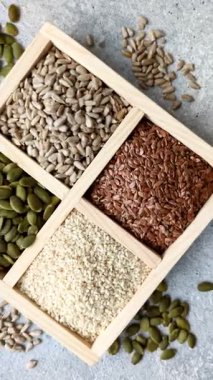 Bir kutu keten, balkabağı, ayçiçeği ve susam tohumu, sağlıklı beslenmek için malzemeler. Keten, susam, balkabağı ve ay çekirdeği tasarımınız için bir besin kaynağı.