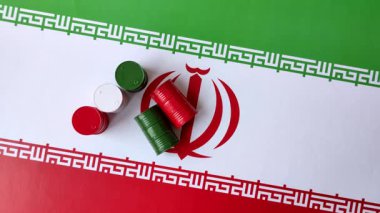 İran bayrağında bulunan petrol, gaz ve kimyasalların metal varilleri. Tasarımınızın arka planı olarak İran petrolü varilleri