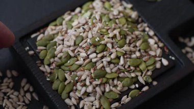 Sağlıklı yiyecekler için kabuklu ayçiçeği, susam, balkabağı ve keten tohumu çekirdekleri. Tasarımınız için gıda arka planı olarak tohumlar ve tahıllar.