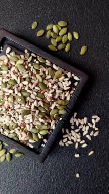 Sağlıklı yiyecekler için kabuklu ayçiçeği, susam, balkabağı ve keten tohumu çekirdekleri. Tasarımınız için gıda arka planı olarak tohumlar ve tahıllar.