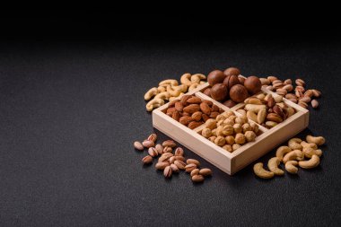 Sağlıklı beslenmek için macadamia fındığı, badem, şam fıstığı ve fındık içeren ahşap kutu. Tasarımınız için yemek arkaplanı olarak fındık