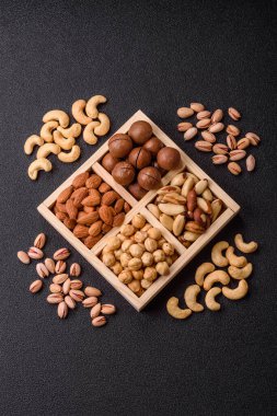 Sağlıklı beslenmek için macadamia fındığı, badem, şam fıstığı ve fındık içeren ahşap kutu. Tasarımınız için yemek arkaplanı olarak fındık