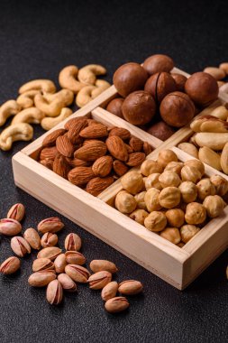 Sağlıklı beslenmek için macadamia fındığı, badem, şam fıstığı ve fındık içeren ahşap kutu. Tasarımınız için yemek arkaplanı olarak fındık