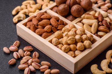 Sağlıklı beslenmek için macadamia fındığı, badem, şam fıstığı ve fındık içeren ahşap kutu. Tasarımınız için yemek arkaplanı olarak fındık