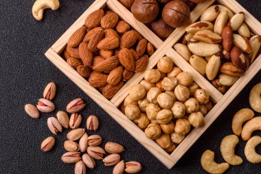 Sağlıklı beslenmek için macadamia fındığı, badem, şam fıstığı ve fındık içeren ahşap kutu. Tasarımınız için yemek arkaplanı olarak fındık