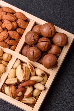 Sağlıklı beslenmek için macadamia fındığı, badem, şam fıstığı ve fındık içeren ahşap kutu. Tasarımınız için yemek arkaplanı olarak fındık