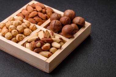 Sağlıklı beslenmek için macadamia fındığı, badem, şam fıstığı ve fındık içeren ahşap kutu. Tasarımınız için yemek arkaplanı olarak fındık