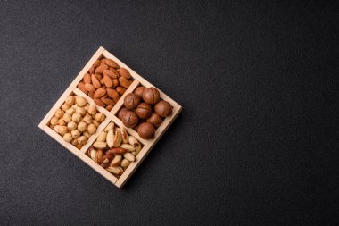 Sağlıklı beslenmek için macadamia fındığı, badem, şam fıstığı ve fındık içeren ahşap kutu. Tasarımınız için yemek arkaplanı olarak fındık