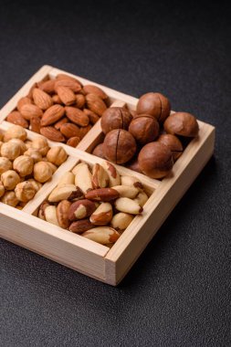 Sağlıklı beslenmek için macadamia fındığı, badem, şam fıstığı ve fındık içeren ahşap kutu. Tasarımınız için yemek arkaplanı olarak fındık