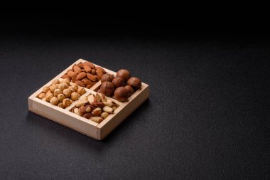 Sağlıklı beslenmek için macadamia fındığı, badem, şam fıstığı ve fındık içeren ahşap kutu. Tasarımınız için yemek arkaplanı olarak fındık