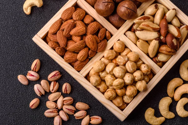Sağlıklı beslenmek için macadamia fındığı, badem, şam fıstığı ve fındık içeren ahşap kutu. Tasarımınız için yemek arkaplanı olarak fındık