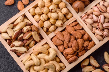 Sağlıklı gıda malzemesi olarak kaju, fıstık, badem, Brezilya fındığı, macadamia ve fındık karışımı. Tasarımınız için yemek arkaplanı olarak fındık
