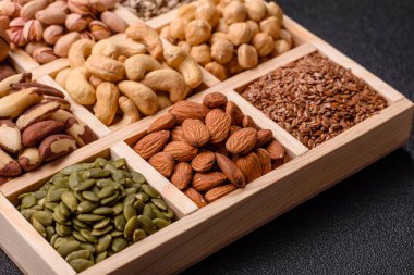 Sağlıklı gıda malzemesi olarak kaju, fıstık, badem, Brezilya fındığı, macadamia ve fındık karışımı. Tasarımınız için yemek arkaplanı olarak fındık