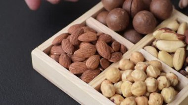 Sağlıklı beslenmek için macadamia fındığı, badem, şam fıstığı ve fındık içeren ahşap kutu. Tasarımınız için yemek arkaplanı olarak fındık