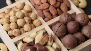 Sağlıklı beslenmek için macadamia fındığı, badem, şam fıstığı ve fındık içeren ahşap kutu. Tasarımınız için yemek arkaplanı olarak fındık