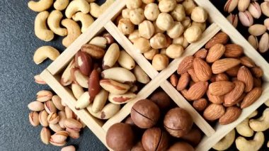 Sağlıklı beslenmek için macadamia fındığı, badem, şam fıstığı ve fındık içeren ahşap kutu. Tasarımınız için yemek arkaplanı olarak fındık