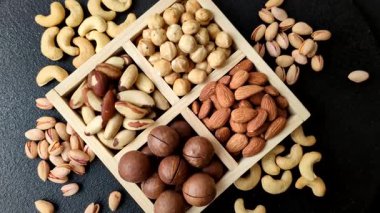 Sağlıklı beslenmek için macadamia fındığı, badem, şam fıstığı ve fındık içeren ahşap kutu. Tasarımınız için yemek arkaplanı olarak fındık