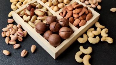 Sağlıklı beslenmek için macadamia fındığı, badem, şam fıstığı ve fındık içeren ahşap kutu. Tasarımınız için yemek arkaplanı olarak fındık