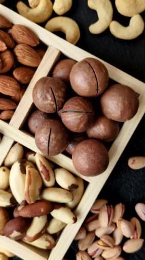 Sağlıklı beslenmek için macadamia fındığı, badem, şam fıstığı ve fındık içeren ahşap kutu. Tasarımınız için yemek arkaplanı olarak fındık