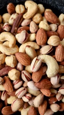 Sağlıklı gıda malzemesi olarak kaju, fıstık, badem, Brezilya fındığı, macadamia ve fındık karışımı. Tasarımınız için yemek arkaplanı olarak fındık