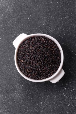 Bir kasede siyah susam tohumu, yağ ve sağlıklı yemek için bir malzeme. Tasarımınız için yiyecek arkaplanı olarak siyah susam