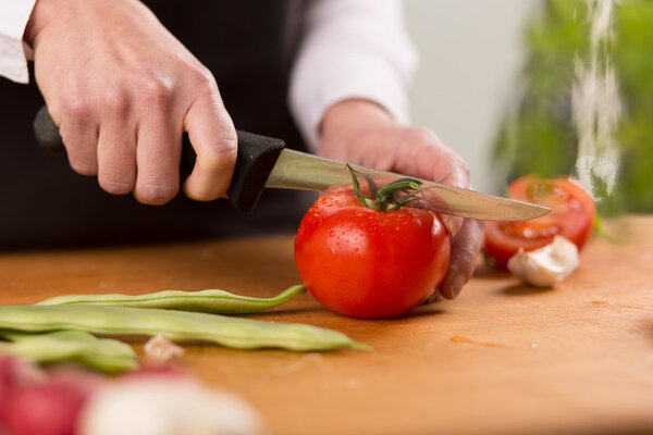 Female hands chopping fresh tomato