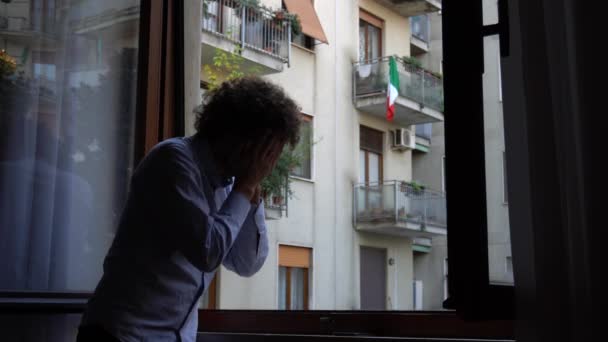 ヨーロッパ イタリア ミラノ マスクで隔離された自宅で40歳の男は パンデミック時に窓の外を見るCovid 19コロナウイルス 流行中のライフスタイル — ストック動画