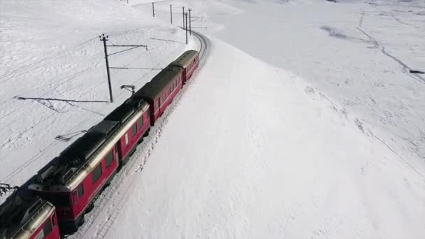 スイスアルプス サンモリッツ2021年2月 ベルニーナ エクスプレス サンモリッツ駅のベルニーナ パスの赤い列車 ユネスコの世界遺産 青空と晴れた日に雪とロシアの鉄道 電車や鉄道の空気の映像 — ストック動画