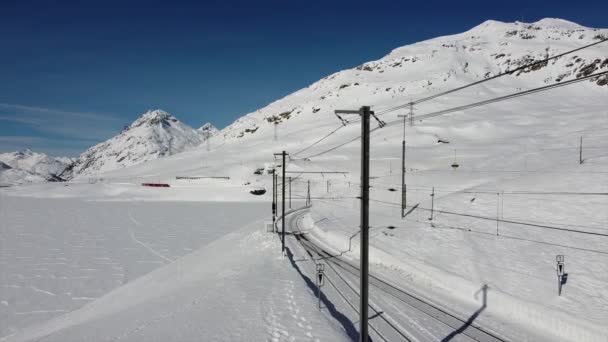 瑞士阿尔卑斯山 圣莫里茨2021年2月 贝尼纳特快 圣莫里茨车站的红色贝尼纳特快道 联合国教科文组织世界遗产 莱茵铁路 雪天晴朗 有蓝天 火车和铁路上有航拍 — 图库视频影像