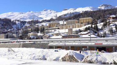 İsviçre Alpleri, Saint Moritz Şubat 2021 - Ünlü otel, çam ağacı ormanı ve dağların tepesinde kar ve buzulla kaplı dağ manzarası 