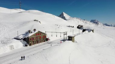 İsviçre Alpleri, Poschiavo Şubat 2021 - Bernina Express 'in insansız hava aracı görüntüsü, Bernina' nın Ospizio Bernina istasyonundaki kırmızı treni - Unesco dünya mirası - Lago Bianco (beyaz göl) 