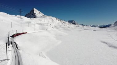İsviçre Alpleri, Saint Moritz Şubat 2021 - Bernina Ekspresi, Saint Moritz istasyonundaki Bernina treni - Unesco dünya mirası - güneşli bir günde güneşli bir tren yolu, mavi gökyüzü ve tren yolu üzerindeki hava görüntüleri 