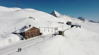 İsviçre Alpleri, Poschiavo Şubat 2021 - Bernina Express 'in insansız hava aracı görüntüsü, Bernina' nın Ospizio Bernina istasyonundaki kırmızı treni - Unesco dünya mirası - Lago Bianco (beyaz göl) 