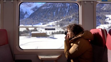 Gezgin blogcu Kafkasyalı 40 yaşında dağ manzarası gezisi sırasında tren penceresinden fotoğraf ve video çekiyor. Bernina Express, Unesco miras dünyası. 