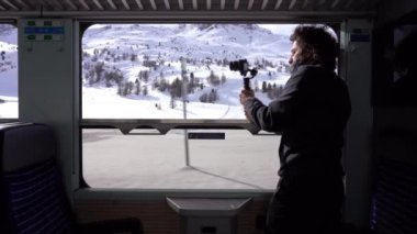 Gezgin blogcu Kafkasyalı 40 yaşında dağ manzarası gezisi sırasında tren penceresinden fotoğraf ve video çekiyor. Bernina Express, Unesco miras dünyası. 