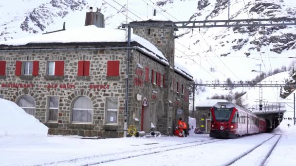 スイスアルプス サンモリッツ2021年2月 ベルニーナ エクスプレス サンモリッツ駅のベルニーナ パスの赤い列車 ユネスコの世界遺産 青空と晴れた日に雪とロシアの鉄道 — ストック動画