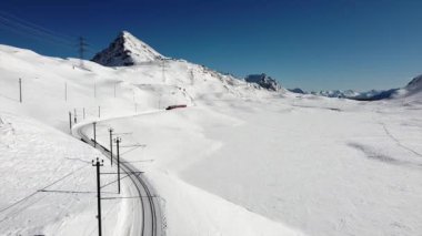 İsviçre Alpleri, Poschiavo Şubat 2021 - Bernina Express 'in insansız hava aracı görüntüsü, Bernina' nın Ospizio Bernina istasyonundaki kırmızı treni - Unesco dünya mirası - Lago Bianco (beyaz göl) 