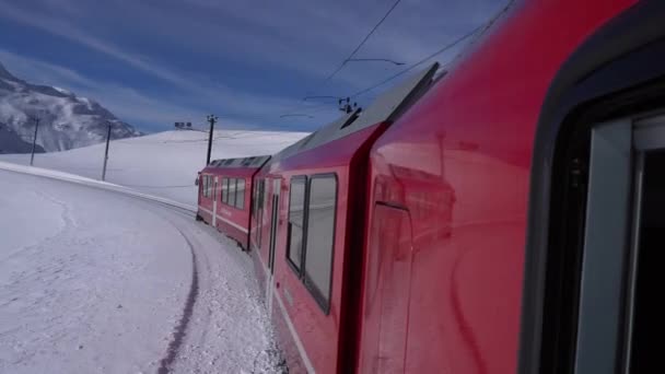 スイスアルプス サンモリッツ2021年2月 ベルニーナ エクスプレス サンモリッツ駅のベルニーナ パスの赤い列車 ユネスコ世界遺産 青空と晴れた日に雪とロシアの鉄道 鉄道の列車からの映像 — ストック動画