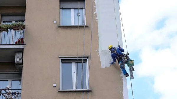 MILAN Nisan 2021 - Yüksek bir binanın şantiyesinde çalışan erkekler. Yüksek irtifa mühendisliği tasarımı için tehlikeli bir iş. Boyama ve dekorasyon binaları. Erkekler evin duvarlarına tırmanıyor.