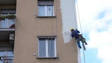 MILAN Nisan 2021 - Yüksek bir binanın şantiyesinde çalışan erkekler. Yüksek irtifa mühendisliği tasarımı için tehlikeli bir iş. Boyama ve dekorasyon binaları. Erkekler evin duvarlarına tırmanıyor.