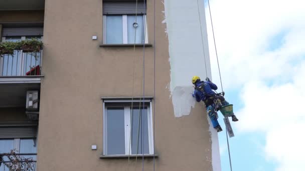 ミラノエイプリル2021 高層ビルの建設現場で働く男性 高高度エンジニアリング設計における危険な作業 絵画や建物を飾る 家の壁を登る男たちは — ストック動画