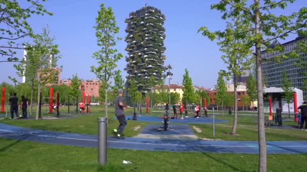 ヨーロッパ イタリア ミラノ2021年4月 Covid 19コロナウイルスのロックダウン後に来る春 ダウンタウンの花と自然 ユニクレディットタワーと垂直の森 人々は公園でジムスポーツ屋外 — ストック動画